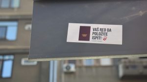 A sign with a sticker on it in front of a building